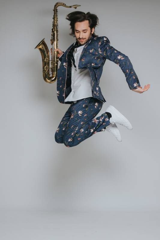 ben sax jumping in the air with saxophone