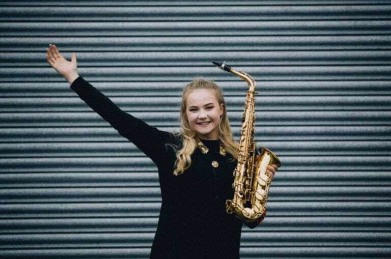 miss sax posing holding saxophone with arm in the air