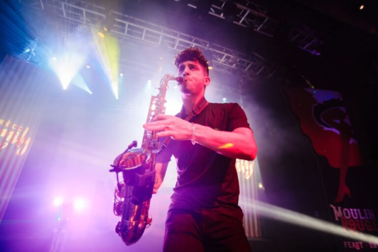 picture of John on sax holding saxophone with smoke min background