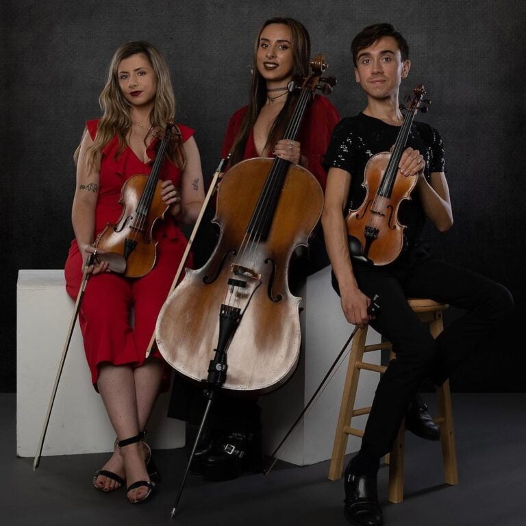 Picture of the string trio and the ladies in red dresses.